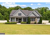 Charming craftsman-style home with gray siding, stone accents, a manicured lawn and a well-kept front yard at 195 Berry Hill Ln, Tyrone, GA 30290