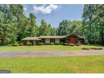 Charming ranch style home with lush greenery and mature trees surrounding the property at 2400 White Pine Ln, Mansfield, GA 30055