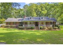 Charming brick home featuring a welcoming front porch with white railings and meticulously landscaped yard at 603 Lakewood Dr, Social Circle, GA 30025