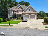 Charming two-story brick home with a manicured lawn, mature trees, and a two-car garage at 1292 Hidden Spirit Trl, Lawrenceville, GA 30045