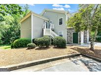 Two-story home with light gray siding, stone accents, stairs, and lush landscaping at 512 Las Brasis Ct, Peachtree City, GA 30269