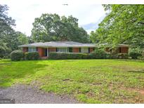 Charming brick home with lush landscaping and mature trees on an expansive green lawn at 2742 Highway 20 W, Hampton, GA 30228