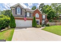 Charming two-story home featuring a brick facade, gray siding, an attached garage, and a well-manicured front lawn at 130 Bexar Ct, Johns Creek, GA 30022