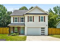 Charming two-story home with a well-manicured lawn, light blue front door, and a spacious two-car garage at 9477 Forest Knoll Dr, Jonesboro, GA 30238