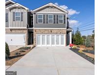 Charming two-story townhome with brick accents, white garage doors, and manicured landscaping at 11555 Kimberly Way, Hampton, GA 30228