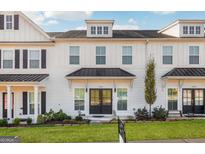 Charming townhome with white siding, black roof, and a well-manicured lawn and landscaped garden at 1848 Eastmore Ave, Conyers, GA 30094