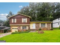 Charming split-level home featuring a brick and wood facade, attached garage, and a well-manicured lawn at 1517 Indian Forest Trl, Stone Mountain, GA 30083