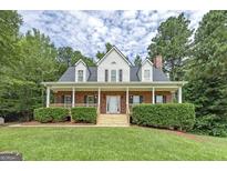 Charming two-story brick home with a welcoming front porch and well-manicured landscaping at 949 Amelia Rd, Locust Grove, GA 30248