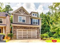 Charming two-story home featuring a stone facade, two-car garage, and well-manicured landscaping at 121 Wellbrook Circle Ne, Conyers, GA 30012