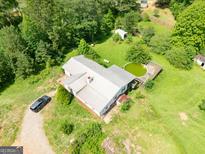 Aerial view of a home with a pool surrounded by lush trees and a car parked in the driveway at 24 Shiloh Church Rd, Carrollton, GA 30116