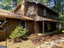 Charming two-story home with wood siding, brick chimney, and covered front porch at 963 Blackberry Ct, Ellenwood, GA 30294
