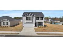 Charming two-story home featuring a gray exterior, a two-car garage, and manicured landscaping at 8587 Secretariat Dr, Lithonia, GA 30058