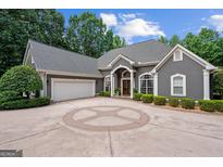 Elegant gray stucco home featuring circular driveway, three-car garage, and manicured landscaping at 9125 Patrick Pl, Winston, GA 30187
