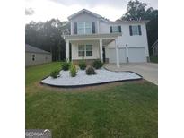 Charming two-story home featuring a welcoming front porch, manicured lawn, and a two-car garage at 160 Grafton St, Hampton, GA 30228