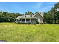 Charming home with stone and siding exterior, covered porch, and lush green lawn, perfect for outdoor enjoyment at 10215 Creel Rd, Chattahoochee Hills, GA 30213