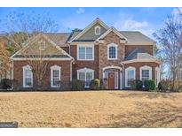 Charming two-story brick home with lush front lawn and manicured landscaping, under a bright blue sky at 6142 Golf View Xing, Locust Grove, GA 30248