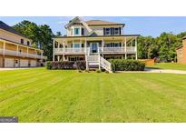 Charming two-story home with a large front yard and inviting wraparound porch with white railing at 27 Riverview, Euharlee, GA 30145