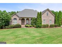 Charming brick home with well-manicured lawn, mature trees and manicured shrubbery at 230 Hummingbird Ct, Hampton, GA 30228