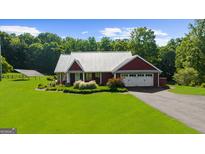 Charming single-story home features a metal roof, an attached garage, manicured lawn and solar panels for energy efficiency at 4335 Hurt Bridge Lane, Cumming, GA 30028