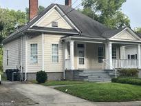 Charming two-story home with a covered front porch and a well-maintained lawn and mature trees at 3155 E Point St, East Point, GA 30344