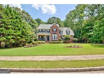Two-story brick home with a manicured front lawn, landscaped flowerbeds, and mature trees at 145 Driftwood Trl, Fayetteville, GA 30215