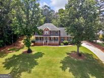 Stately brick home with a lush green lawn and mature trees offering curb appeal and a welcoming entrance at 416 River Forest Dr, Mcdonough, GA 30252