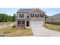 Charming two-story home featuring brick and gray siding, black shutters, manicured lawn, and an attached two-car garage at 612 Whitman Ln, Stockbridge, GA 30281