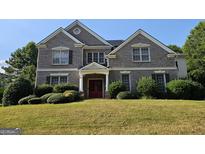 Charming brick home featuring a manicured lawn, symmetrical design, and a welcoming double-door entrance at 7235 Thoreau Cir, Atlanta, GA 30349