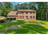 Charming brick two-story home with red shutters and a well-manicured lawn surrounded by mature trees at 305 Brandon Mill Cir, Fayetteville, GA 30214