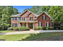 Charming two-story brick home featuring a manicured lawn and inviting front porch at 100 Old Plantation Way, Fayetteville, GA 30214
