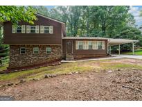 Charming home with a brick and wood exterior, complemented by well-maintained landscaping and a carport at 954 Camp Creek Sw Dr, Lilburn, GA 30047