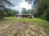 Single story home with a covered front porch, and an expansive front yard surrounded by mature trees at 3144 Clemons Rd, Stockbridge, GA 30281
