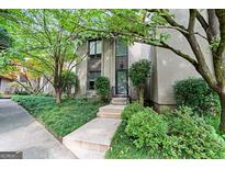 Charming townhome entrance with lush landscaping, stone walkway, and a modern glass front door at 32 Ivy Ne Pkwy, Atlanta, GA 30342