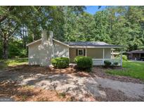 Charming single-story home with a brick chimney, a quaint front porch, and mature landscaping at 6770 Burkhead Dr, Union City, GA 30291