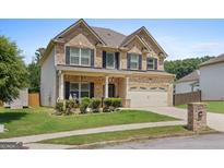 Charming two-story brick home featuring a covered front porch, attached two car garage and landscaped front yard at 4770 Macy Way, Ellenwood, GA 30294