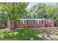 Charming brick home with blue shutters, surrounded by mature trees and a lush green lawn at 1737 Cahoon Sw St, Atlanta, GA 30310