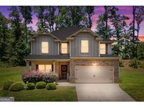 Charming two-story home with a brick-accented front and attached two-car garage, set against a backdrop of lush greenery at 470 Louise Way, Locust Grove, GA 30248