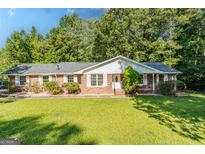 Charming brick home with a well-manicured lawn and mature trees offering an inviting curb appeal at 115 Brookwood Ln, Fayetteville, GA 30215