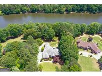 Aerial view of a brick home surrounded by mature trees, with river access and a well-manicured lawn at 660 Milton Dr, Mcdonough, GA 30252
