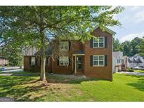 Traditional two-story brick home with a well-manicured front yard, under a large tree at 2326 Sand Dollar Sw Ct, Atlanta, GA 30331