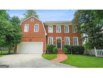 Beautiful two-story brick home with a well-manicured lawn, attached garage, and brick pathway at 1186 Village Ne Cv, Atlanta, GA 30319