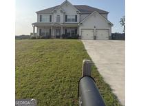 Two-story home boasts an attached two-car garage and a well-manicured lawn at 64 N Village Cir, Rydal, GA 30171