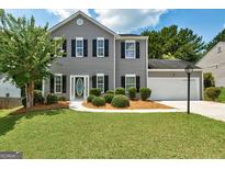 Charming two-story home featuring grey siding, black shutters, landscaped lawn, and attached garage at 3953 Willow Fields Ct, Loganville, GA 30052