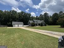Beautiful two-story home features a long drive, lush lawn, and a detached two-car garage at 180 Cooper Rd, Social Circle, GA 30025
