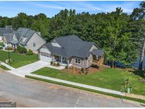 Lakefront Craftsman-style home boasts a manicured lawn, attached garage, and covered deck overlooking the water at 301 Retreat Way, Carrollton, GA 30116