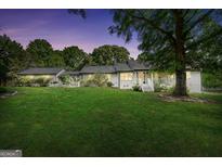 Charming white home with a lush green lawn and mature trees in a serene setting at twilight at 701 Mask Rd, Brooks, GA 30205