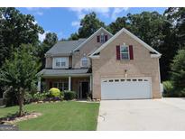 Inviting brick two-story home featuring a well-manicured lawn, two-car garage and charming front porch at 305 Matthew Cir, Stockbridge, GA 30252