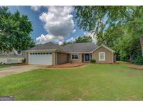 Charming single-story home featuring a manicured lawn, neutral paint, and a two-car garage in a suburban setting at 1615 Clairmont Sw Ln, Conyers, GA 30094