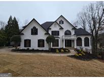 Stunning two-story home with a white stucco exterior, black shutters, a circular balcony, and professionally landscaped yard at 7910 Tintern Trce, Duluth, GA 30097