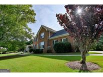 Traditional two-story brick home featuring a well-maintained lawn and mature landscaping at 165 Mcelwaney Way, Fayetteville, GA 30215